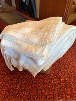 Folded white queen size coverlet with visible lace edge and textured pattern