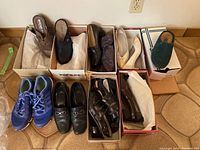 View of 9 pairs of shoes including sneakers, dress shoes and sandals, some in boxes