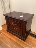 Front angled view of side table showing two drawers with brass handles and dark polished wood finish