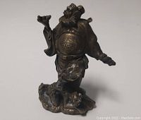 Front view of the old man bronze sculpture showing details of the face, raised hand, and robes.
