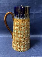 Front view of pitcher showing cobalt blue rim, leaf motif border and slipware body