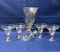 Vintage etched crystal vase and five matching glasses on blue fabric background showing overall condition and set composition.