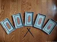 Five rectangular decorative porcelain dishes laid out with one pair of chopsticks crossed in the center, showing lot contents.