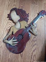 Front view of handcrafted metal art sculpture of a faceless guitarist holding an acoustic guitar, showing colors and artwork details.