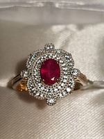 Close-up image of the front face of the ring showing the central ruby surrounded by white topaz stones.