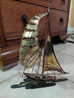 Front angled view of the sailboat metal sculpture showing the curved spinnaker sail and rigging detail.