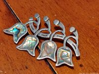 Front view showing four Lily of the Valley shaped flowers with abalone shell insets.