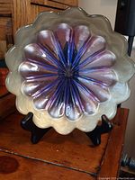 Front view of the vintage carnival glass shallow dish showing iridescent purple and blue petals and scalloped edge.