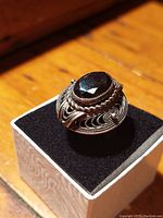 Close-up of vintage silver ring with faceted black hematite stone on black velvet display.