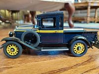 Side view of blue vintage diecast pickup truck with yellow wheels and visible spare tire.