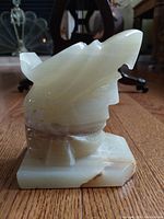 Side view of vintage onyx eagle head sculpture showing natural stone grain and layered color detail, standing on geometric flat base.