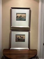 Pair of framed woodblock prints displayed vertically on wall