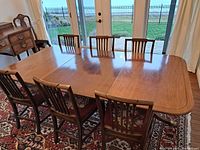 Full frontal view of extended mahogany pedestal dining table with chairs