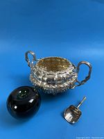Sugar bowl, caddy spoon and scale reference placed on blue background