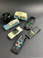 Top view showing all six vintage toy vehicles grouped on a black surface next to a green apple for size reference.