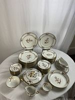 Full set arranged on round draped table showing stacks of plates, bowls, lidded tureen and gravy boat