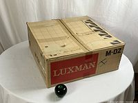 Original cardboard box labeled “LUXMAN M-02” with green apple for scale