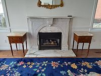 Both side tables positioned on either side of a fireplace showcasing marble tops and overall design.