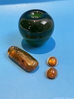 Overview showing sterling silver clip-on earrings, large amber block, and glass apple reference