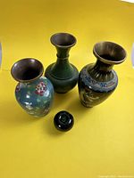 Overview of three enamel vases with green reference apple