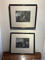 Both framed engravings visible on wall and leaning on table, showing overall lot presentation and condition.