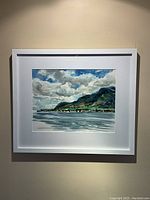 Framed watercolour painting showing coastal mountain landscape under cloudy sky.