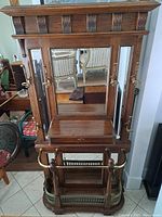 Full front view of oak hall stand showing three beveled mirrors, drawer and umbrella rack
