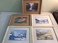 Five framed landscape prints arranged on a table showing diverse scene compositions