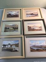 Six framed watercolor prints arranged in two rows of three on a table, showing various Scottish landscapes
