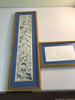 Full image showing the two framed pieces: the narrow vertical silk embroidery panel and the horizontal framed letter with provenance information and history.