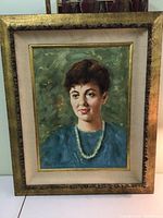 Full view of the framed portrait of a woman in a blue dress with pearl necklace, artist Leon Franks signature visible.