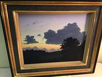 Front view of framed painting showing sunset landscape and gold/black frame