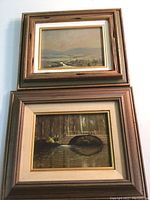 Two framed oil paintings stacked, one showing a bridge scene with two nuns by water beneath a tree canopy, both signed by artist Richard Hinger.