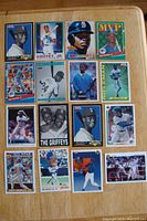 16 Ken Griffey Jr. baseball cards arranged on a wooden table showing fronts, various designs and player images.