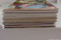 Stack of comics showing thickness and condition, some bagged and boarded, some loose.