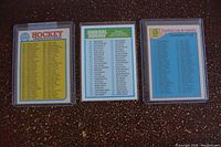 Three hockey card checklists displayed side by side in protective sleeves on a dark surface.