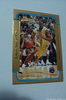 Front side of Chris Bosh gold rookie card showing player action photo, gold border, and team logos.