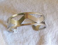 Front view of the hand-crafted burnished sterling silver bracelet showing the open wave cut-out design.