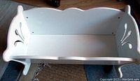 Angled top view of the white wooden cradle interior showing smooth painted interior and sturdy side handles.