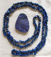 Photo showing full necklace coiled and the pendant laid flat on a fabric background highlighting the polished and raw sides of the stone.