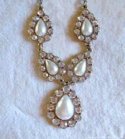 Front view of the statement necklace with teardrop-shaped faux pearls surrounded by clear rhinestones.