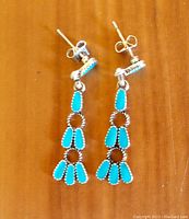 Front view of turquoise silver-tone and enamel dangle earrings showing small blue enamel stones set in silver-tone metal with 2-inch length.
