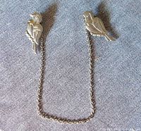 Two sterling silver bird clasps connected by a chain displayed on fabric background, showing front and side views