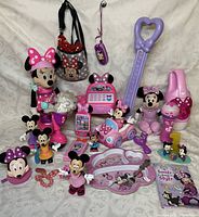 Photo showing full assortment of Minnie Mouse themed collectibles including plush, figurines, toys, and novelty items, mostly in pink and purple shades.