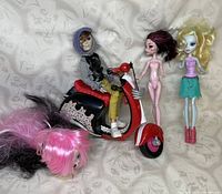 Full view of the lot including Ghoulia Yelps doll on scooter, two dolls standing nude and dressed, detached doll head on its side in front.
