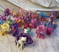 Wide view of 18 My Little Pony figures in various colors and hair styles, showing overall lot condition.