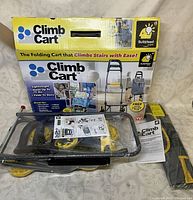 Folded Climb Cart with original box, manual and carrying bag placed on fabric background.