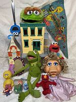 Wide shot of Sesame Street plush characters, toy houses, small collectible figures, and skateboard deck