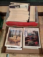 Plastic tote filled with stacked Architectural Digest issues and a cardboard box of magazines in front