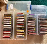 Four clear plastic totes holding stacks of audio CD jewel cases
